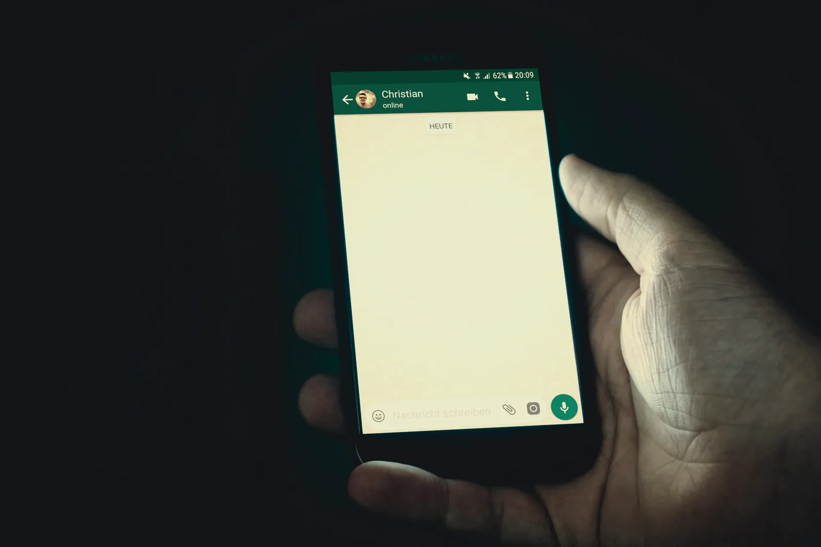 Mão segurando o celular com uma conversa de WhatsApp aberta